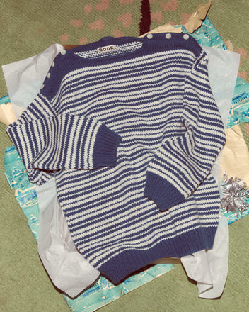 The Peter Stripe Sweater features blue and white stripes with shoulder buttons, made from soft lambswool cashmere, and comes laid on blue tissue paper and gift wrap.
