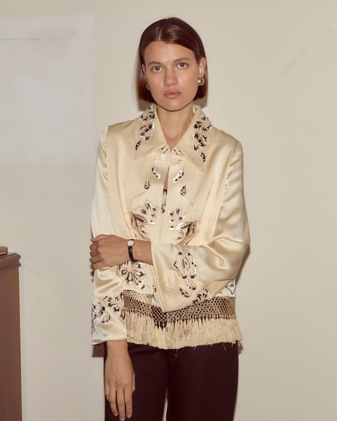 Woman in the Phantasm Fringe Jacket and black pants stands against a beige wall, looking at the camera.