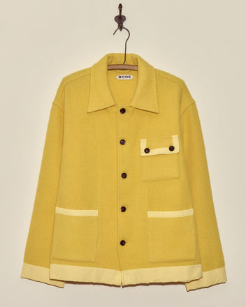 Phosphorus Jacket - M: Yellow midcentury wool jacket with cream trim, front pockets, and a collar, displayed on a hook against a wall.