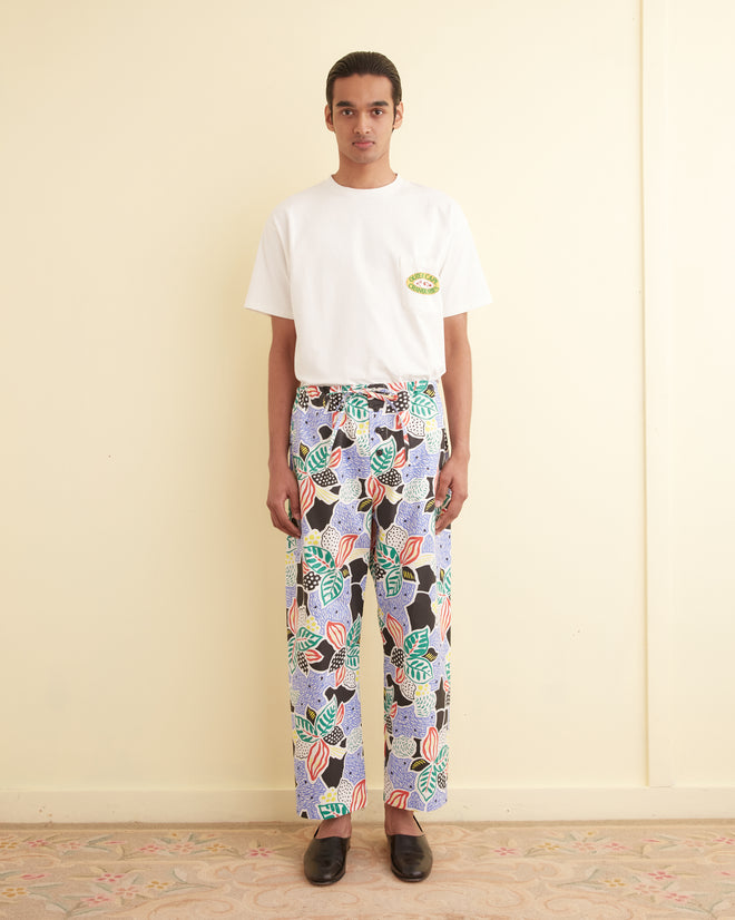 A person in a white t-shirt and Plantain Jazz Pajama Pants stands against a pale wall.