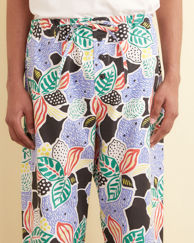 Wearing Plantain Jazz Pajama Pants featuring a vibrant, abstract botanical leaf and polka dot pattern, with hands relaxed by their sides.