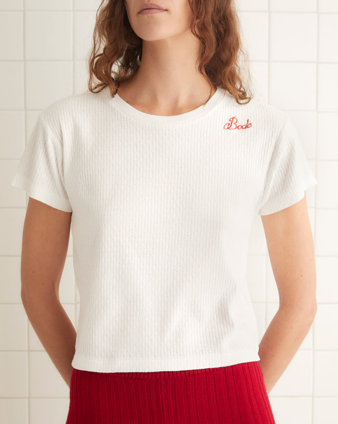 White ribbed cotton short sleeve tee with small red chain-stitch embrodery on left shoulder.