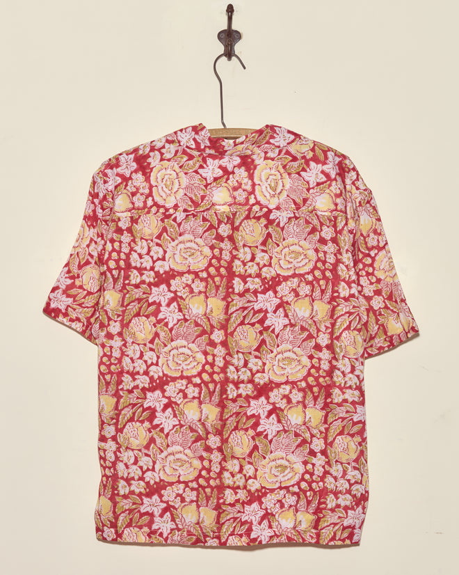 Pomegranate Leaf Short Sleeve Shirt in M/L, featuring a vintage red floral design, hangs on a hook against a plain beige wall.