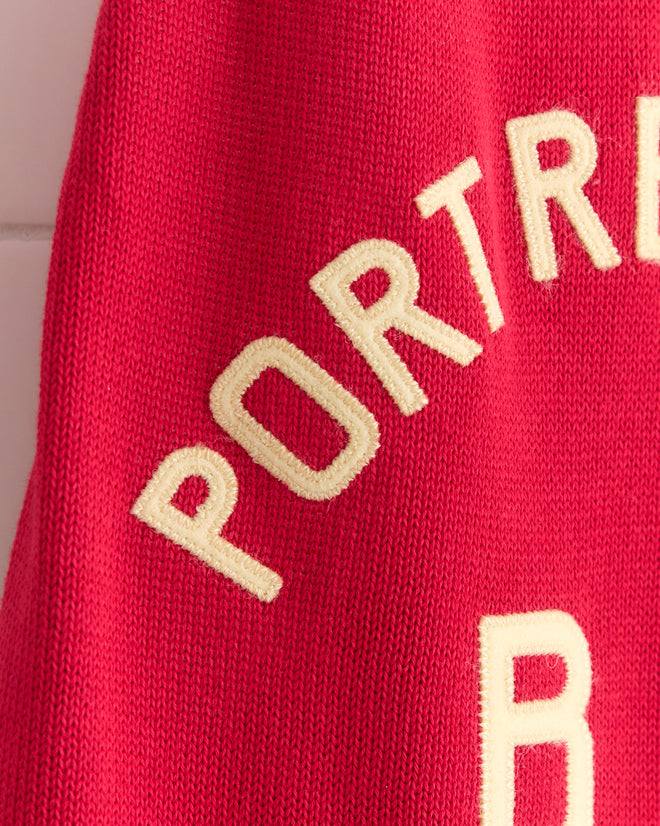The Port Dress features red knit fabric inspired by 1900s–1920s rowing singlets, finished with bold cream "PORTRE" lettering.