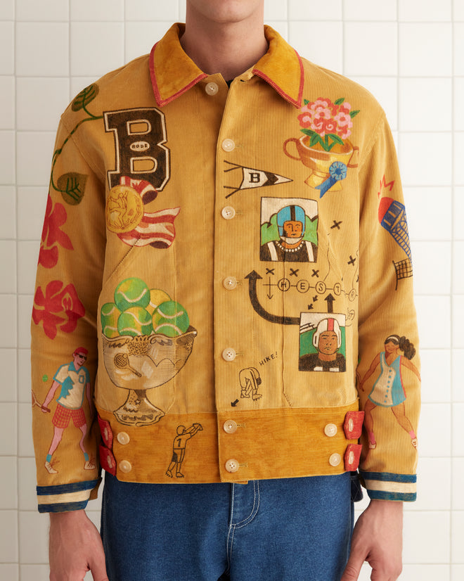 A person wearing a vibrant Bode Recreation Senior Cord Side Tab Jacket, embellished with personalized motifs, stands against a tiled wall in a well-lit room.