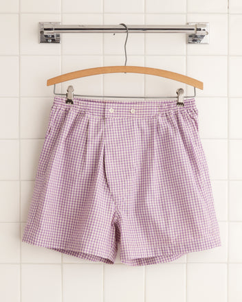 A pair of unique Provence Cream Boxers hang on a wooden hanger against a tiled wall.