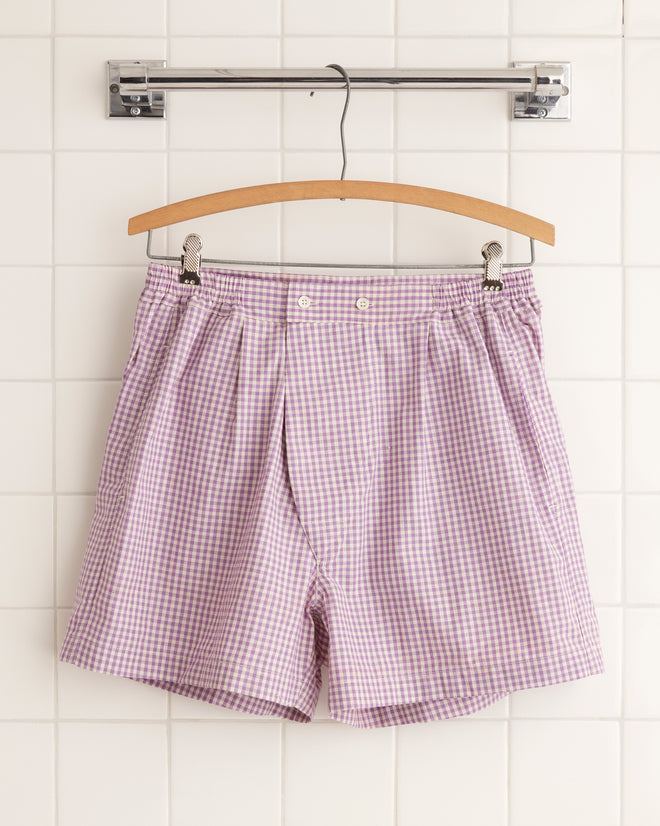 A pair of unique Provence Cream Boxers hang on a wooden hanger against a tiled wall.