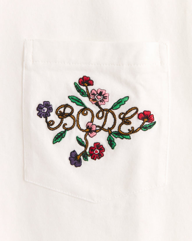 The Posy Pocket Tee features a white pocket embroidered with "BODE" in floral script and colorful flowers for a charming vintage look.