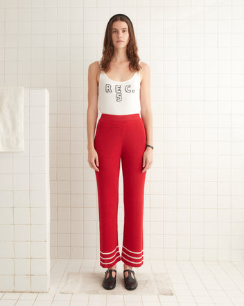 A woman in a white tank top and Quincy Stripe Joggers - Red stands in a tiled room, looking forward.