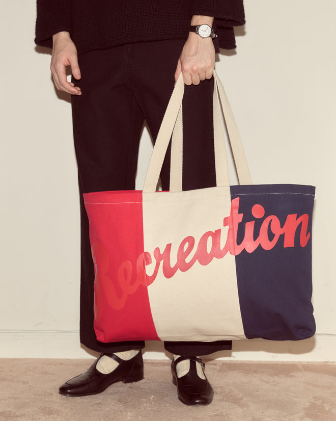 A person holds the Recreation Tote, a large red, white, and blue bag with 