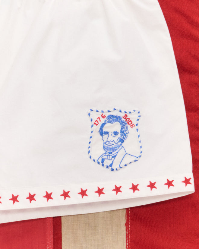 Red Star Tap Shorts feature white fabric with a blue Abraham Lincoln sketch, "1776 1902," and red stars—ideal for Liberty costumes or July Fourth outfits.