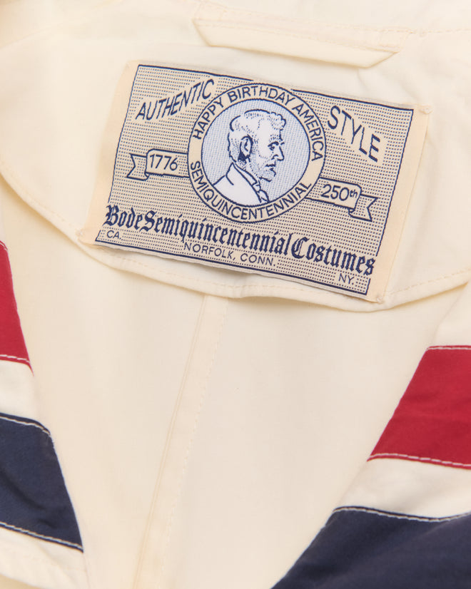 The Centennial Dress - Multi features a "Happy Birthday America" label with a profile portrait and red, white, and blue trim—perfect for Liberty costumes or festive Fourth of July outfits.