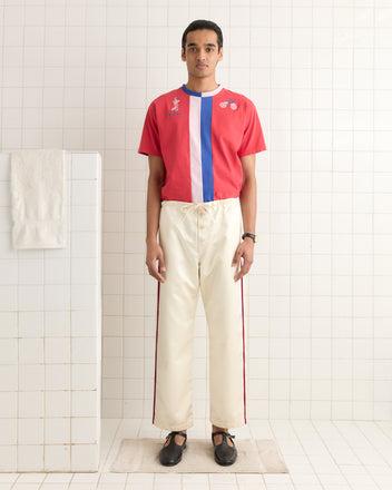 Someone in a red and blue color-blocked shirt paired with Redtail Pajama Pants stands in a white tiled room.