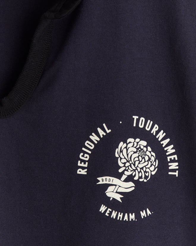 Regionals Polo in navy 100% cotton features a white chrysanthemum corsage graphic and "REGIONAL TOURNAMENT, WENHAM, MA., BODE" text.
