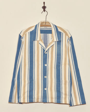 The Riverbed Stripe Long Sleeve Shirt - XL features blue, white, and beige vertical stripes and hangs on a wall hook.
