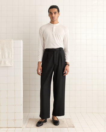 A person in a Salt Marsh Polo and black high-waisted pants stands in a tiled room.