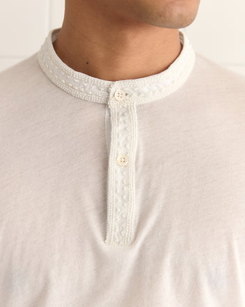 Close-up of someone wearing the Salt Marsh Polo, featuring an off-white shade, decorative collar, button placket, and tonal beadwork.