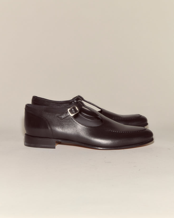 School Shoes - Black: Classic Italian-made black leather shoes with a side buckle in T-strap style, displayed on a neutral background.