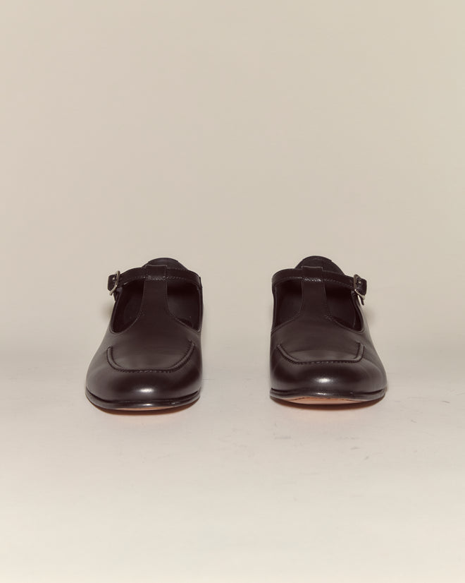 School Shoes - Black: Italian-made black leather T-strap shoes with buckle straps, shown against a plain background.