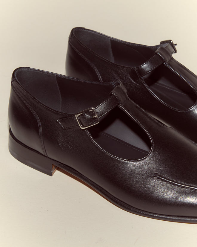 The School Shoes - Black are made in Italy with black leather, featuring T-straps and silver buckles, shown on a light background.