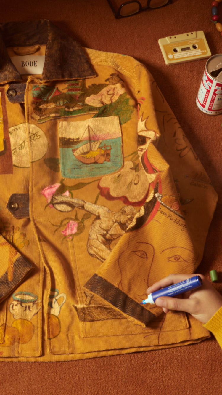 person drawing on Senior Cord Jacket made from corn-colored British corduroy with hand-drawn illustrations