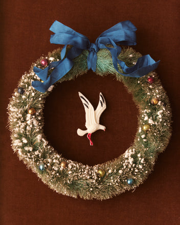 Product Data: Christmas Wreath with Blue Ribbon and Multicolored Ornaments

A Christmas wreath, trimmed with a blue ribbon and vibrant ornaments, showcases a white bird decoration that resembles the silhouette of a diving seagull, all on a brown backdrop.