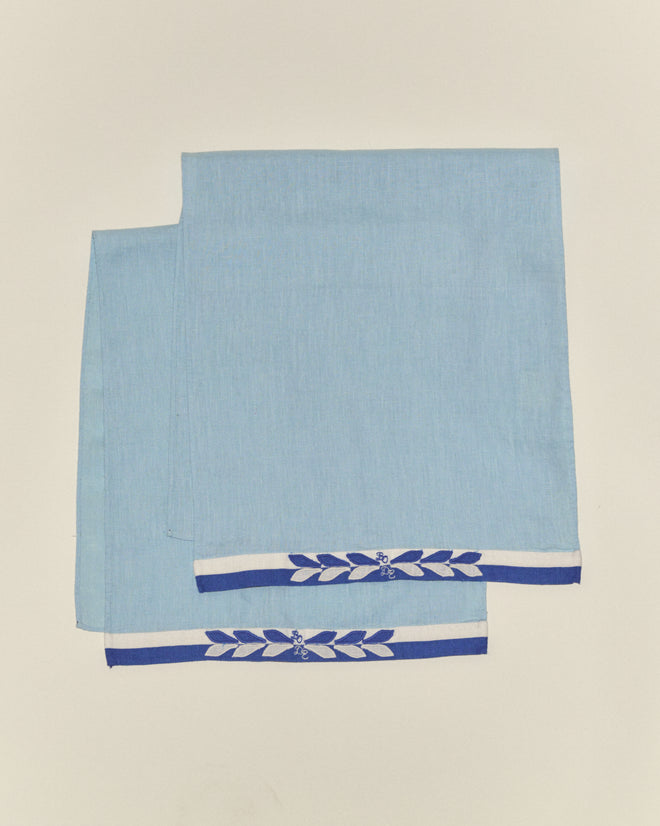 The Seedling Stripe Dish Towels, in light blue with blue and white borders and a delicate floral design, bring the nostalgic charm of midcentury linens to your kitchen.
