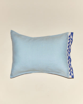 Seedling Stripe Pillowcases: Light blue rectangular pillowcase featuring a blue and white leaf-patterned trim on one edge, inspired by midcentury design, shown against a neutral background.