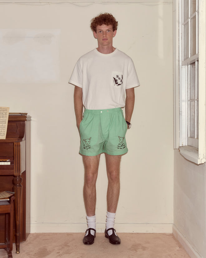 A man stands indoors wearing a white T-shirt, black shoes, white socks, and See You at the Barn Boxers.