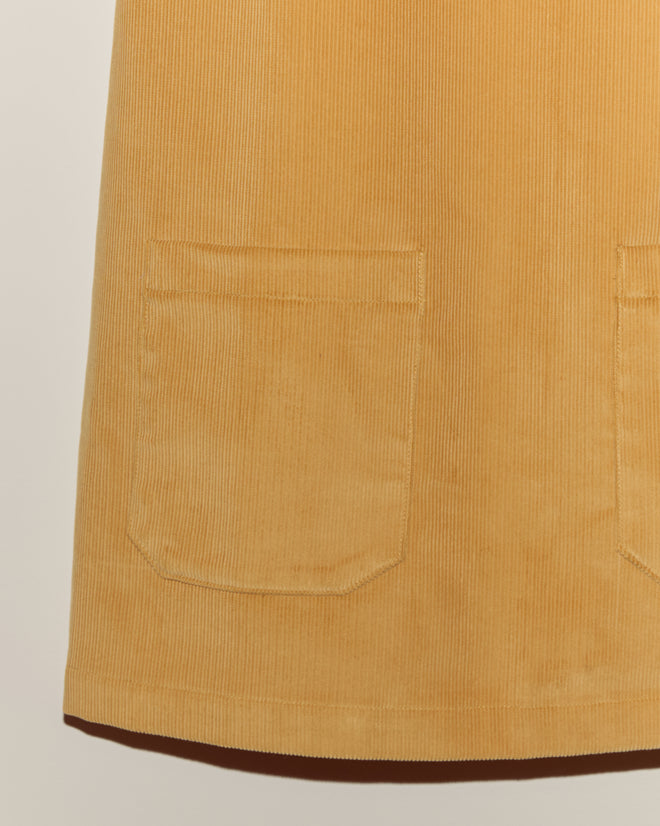 Close-up of a Custom Senior Cord Dress in mustard yellow corduroy with two front pockets, shown against a plain background.