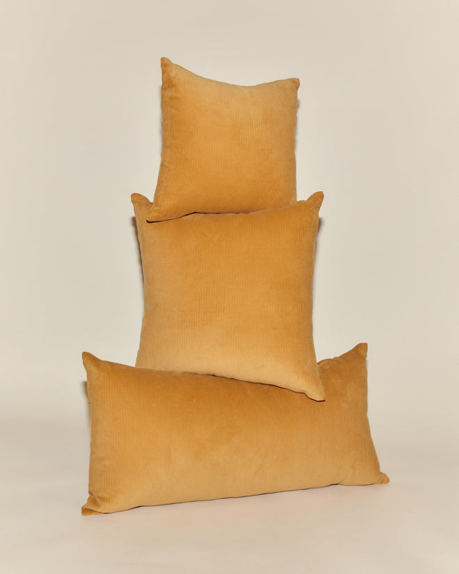 Three Custom Senior Cord Pillows in mustard yellow are stacked in a pyramid on a simple, light background.