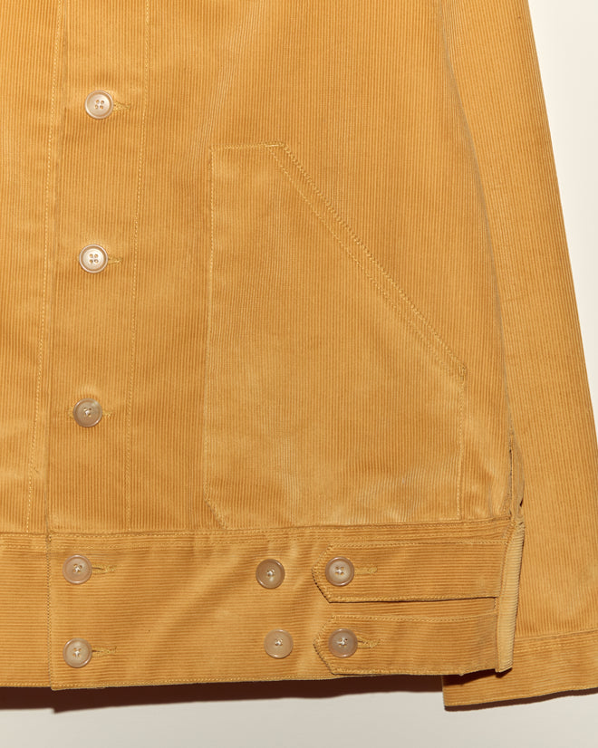 Close-up of a Custom Senior Cord Side Tab Jacket in tan corduroy with buttons and a large front pocket, displayed against a plain background.