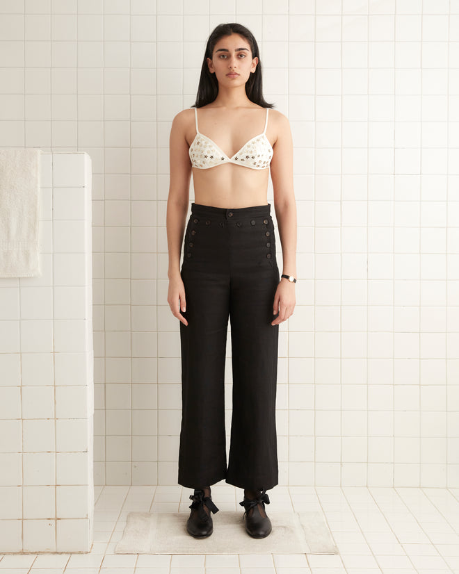 The Sequin Spangled Bra, an Indian-made white bralette, showcases sequined star patterns displayed on a tiled surface.