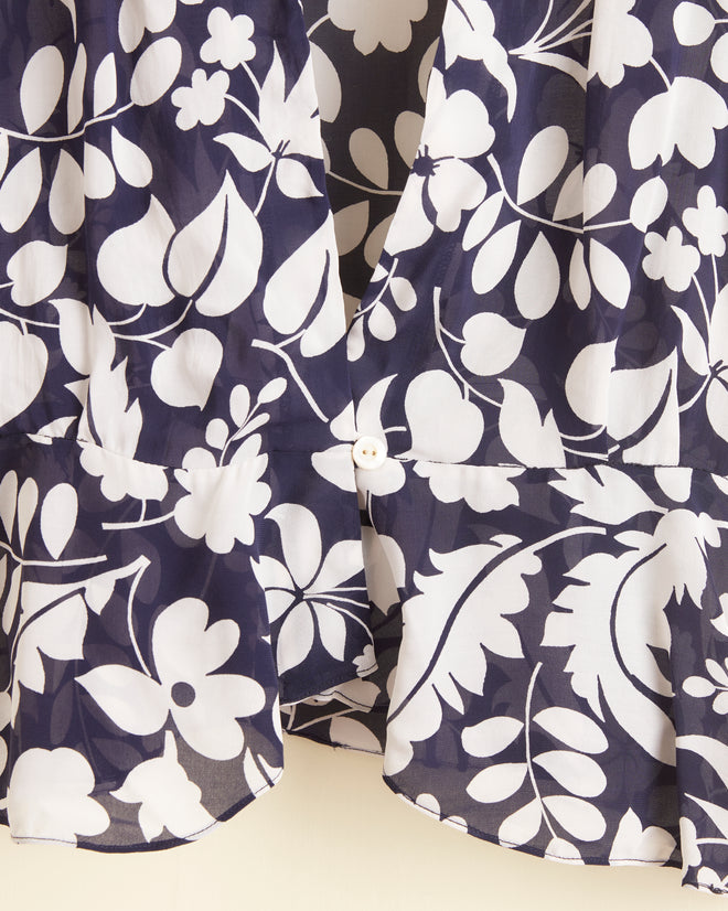 Close-up of the Shadowed Ferns Top - 2, a navy blue shirt made from deadstock dress fabric with a 1940s-inspired white floral pattern and a single button near the bottom center.