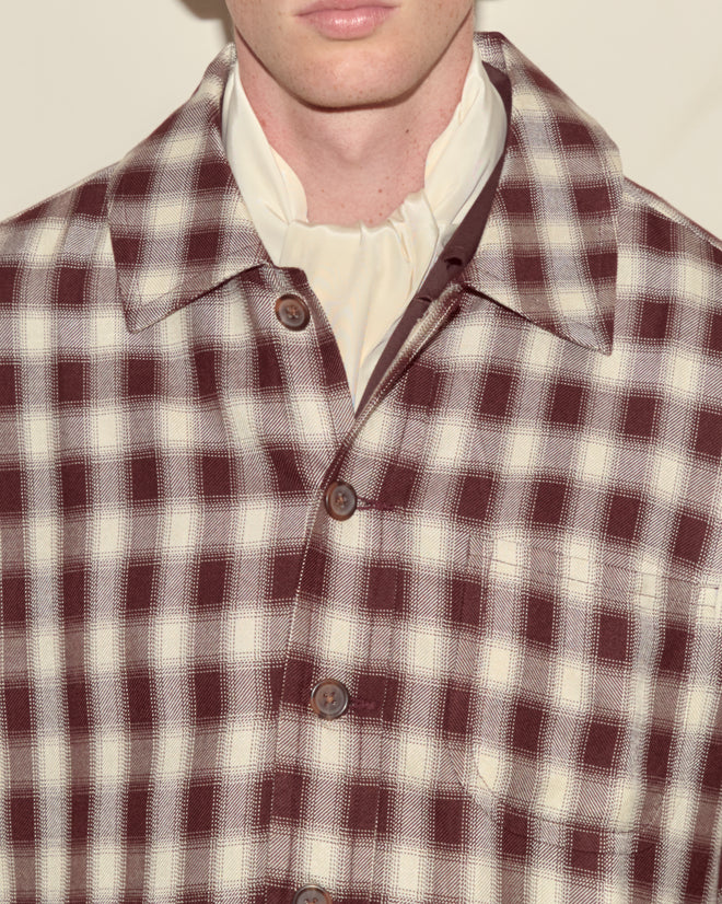 A person wearing the Shadow Plaid Franck Jacket in maroon and white ombré over a cream high-neck shirt.