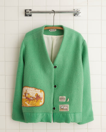 The Shamrock Blanket Jacket - 12, with its distinctive patchwork design, hangs stylishly on a tiled wall.