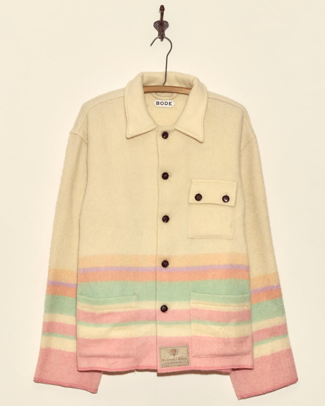 The Sherbet Horizon Jacket - XXL is a midcentury-inspired cream wool button-up with pastel stripes and front pockets, shown hanging on a hook against a beige wall—an elegant, one-of-a-kind piece.