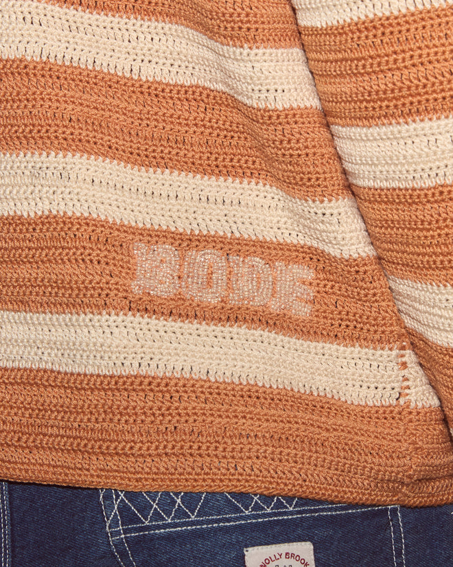 Close-up of a tan and cream Sherbet Crochet Long Sleeve Shirt by BODE with "BODE" stitched; jeans below emphasize the artisanal, handmade-inspired crochet detail.