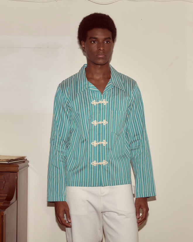 A man wears the Shore Stripe Long Sleeve Shirt, featuring blue and white stripes inspired by 1940s men's style with frog closures.