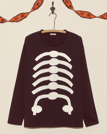Skeleton Long Sleeve Tee in black with glow-in-the-dark white ribcage print, shown on a hanger with Halloween garland in the background.