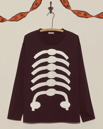 The Skeleton Long Sleeve Tee is a black shirt with a white rib cage print, hanging on a hook beneath an orange Halloween garland—a vintage Halloween classic perfect for spooky season.