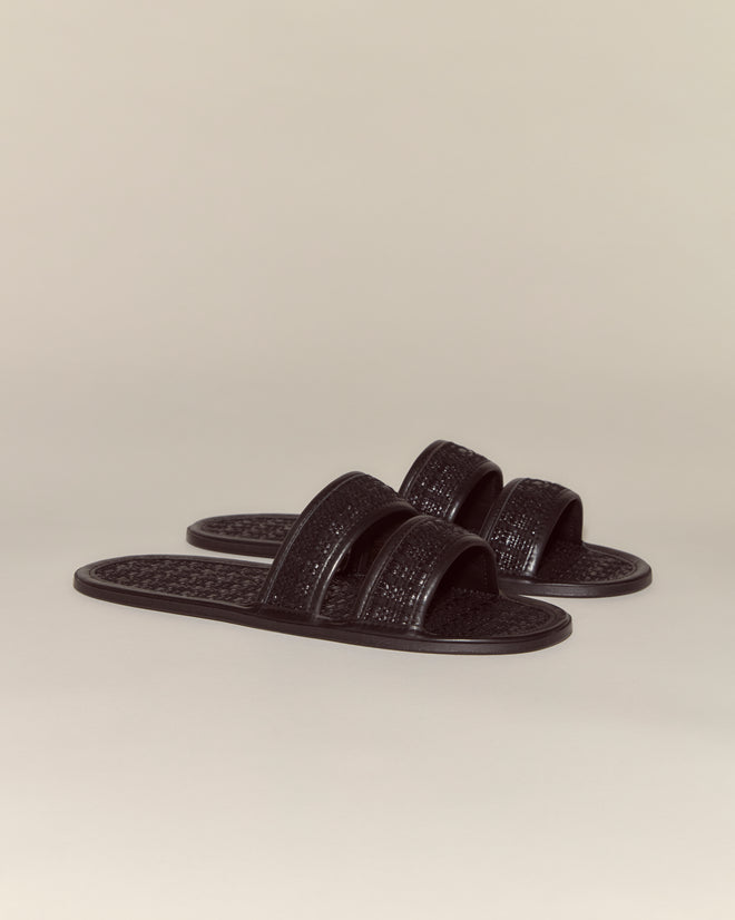 A pair of Solid Summer Slides in black with two straps, crafted from smooth calf leather, displayed on a plain beige background.