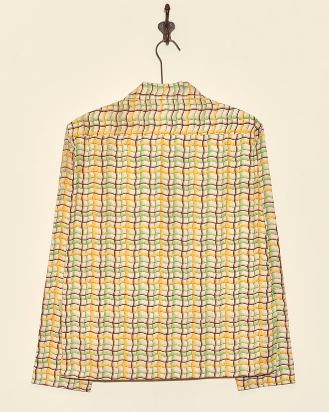 The Sorghum Patch Long Sleeve Shirt (XS) features a unique, colorful geometric pattern and is displayed hanging on a hook against a simple background.