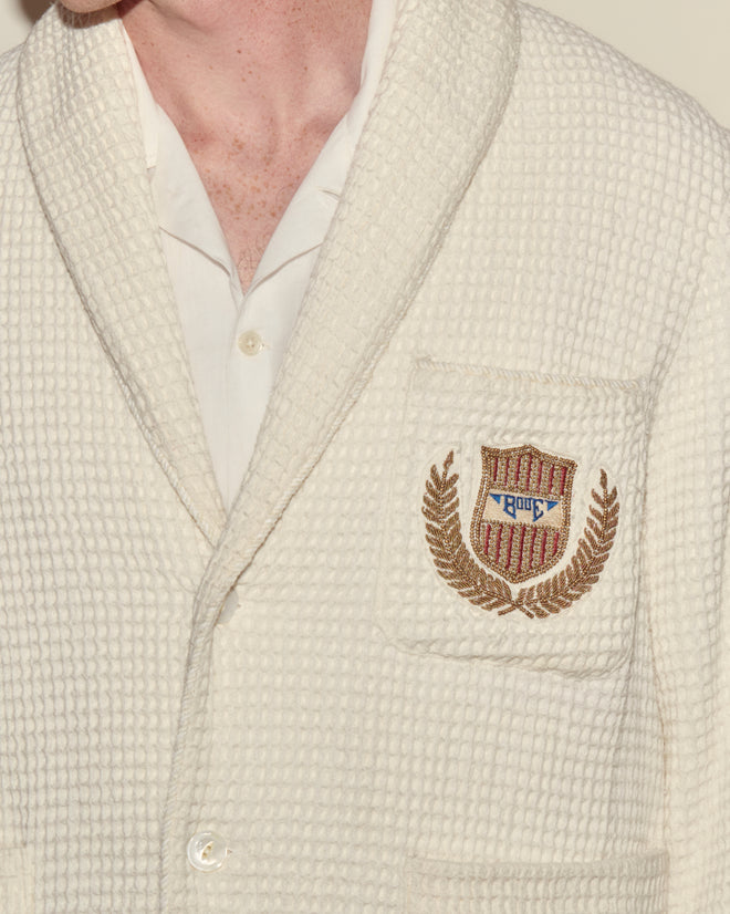 A person wearing a Sportsman Jacket featuring an embroidered bullion crest and "Rque" on the chest pocket.