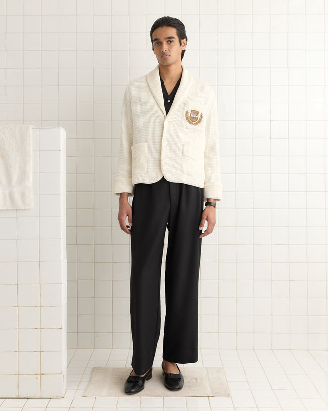 A person in a Sportsman Jacket with an embroidered bullion crest and black pants stands on a tiled floor, facing forward.