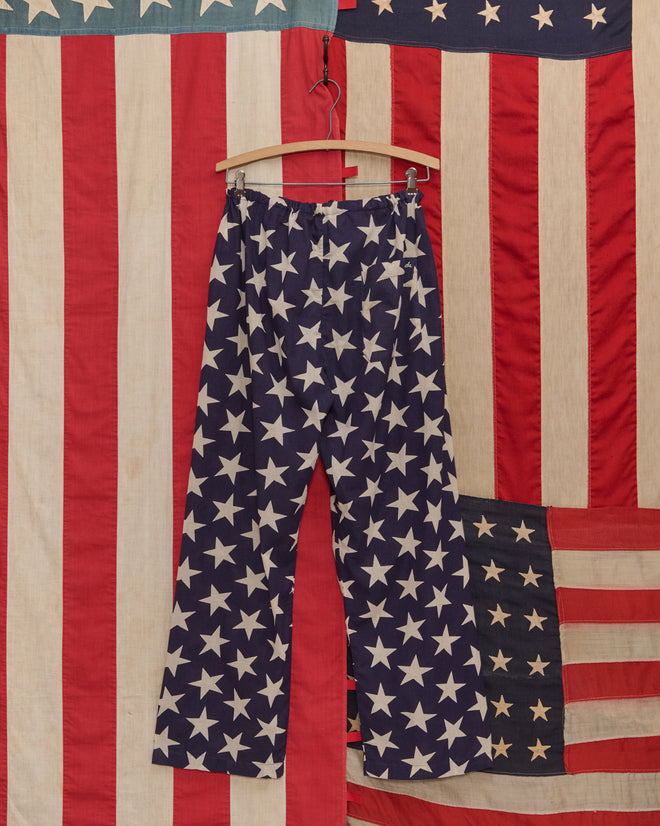 Starry Pajama Pants: Wide-leg 100% cotton pajama pants with white stars on a blue background, shown against an American flag pattern backdrop.