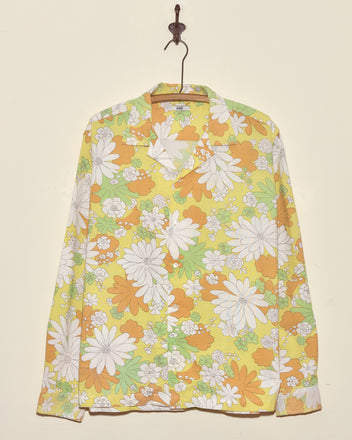 The Storytime Floral Shirt (XL/XXL), crafted from a vintage yellow, orange, and white floral bedsheet, hangs on a hanger.
