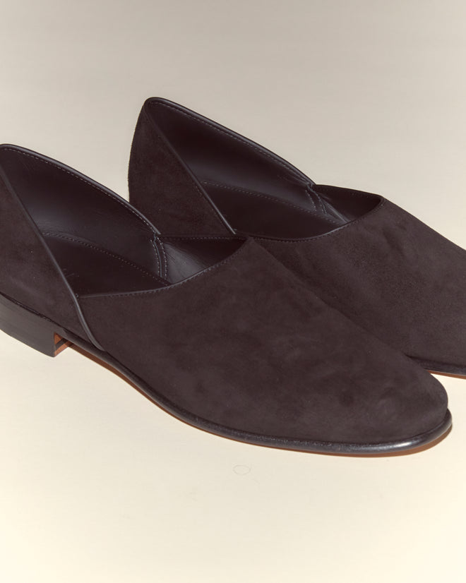 The Suede House Shoes - Black are crafted from Italian suede with a leather sole and low heels, shown against a light background.