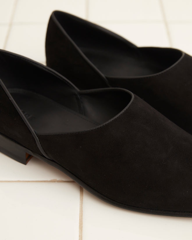 The Suede House Shoes in black, resting on a white tiled floor, exude the timeless elegance of Italian footwear.