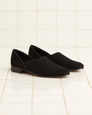 The Suede House Shoes in black, resting on a white tiled floor, exude the timeless elegance of Italian footwear.